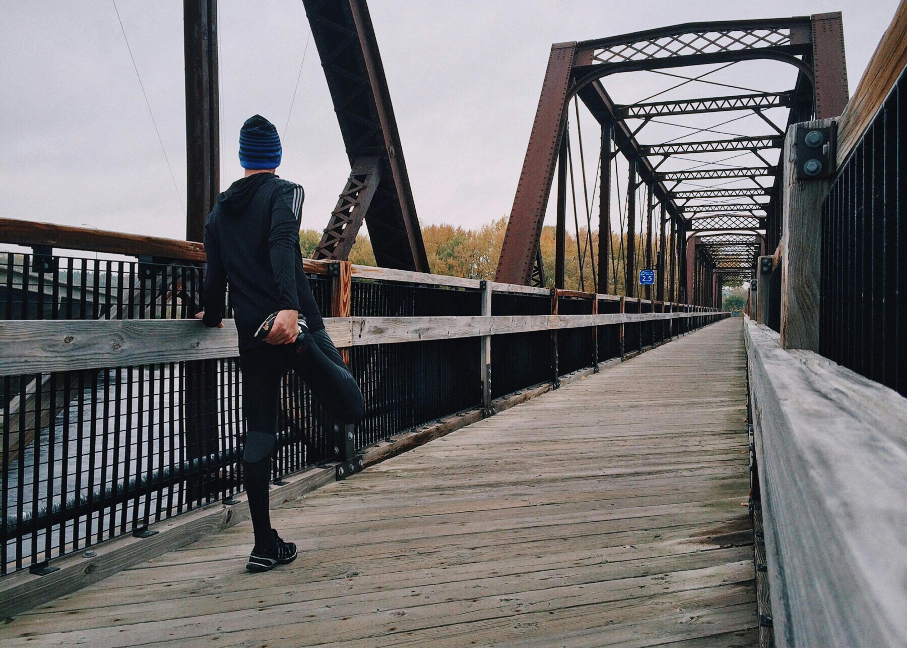 Runner lacing shoes at sunrise with a gift box and race bib on a bench